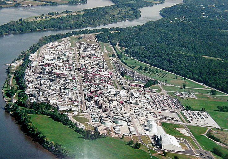 an aerial view of a large city next to a body of water with trees in the background