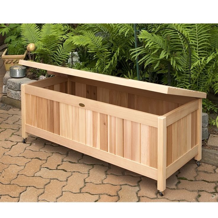 a large wooden box sitting on top of a stone floor next to plants and potted plants