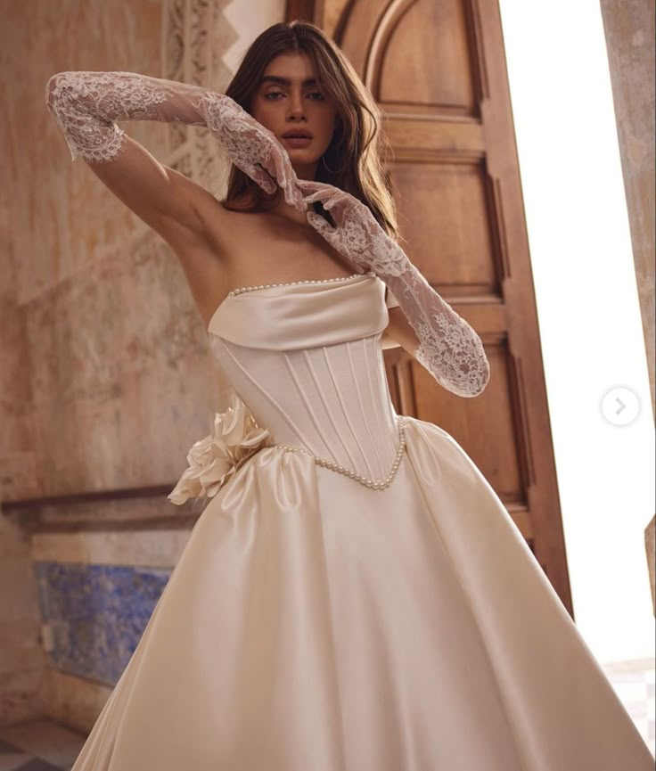 a woman in a white wedding dress is posing for the camera with her arms behind her head