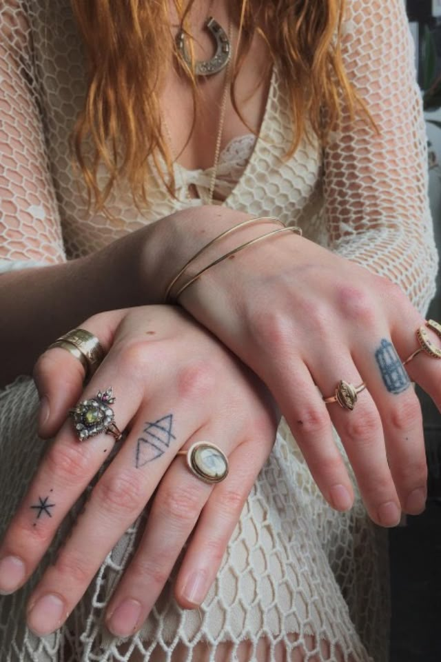 two people with tattoos on their hands and fingers, one holding the other's hand