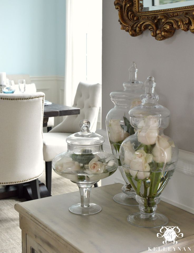 two vases filled with flowers sitting on top of a table next to a mirror