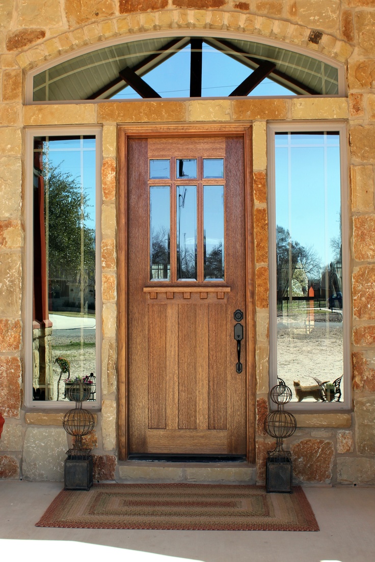 the front door is made of wood and has two planters with flowers in them