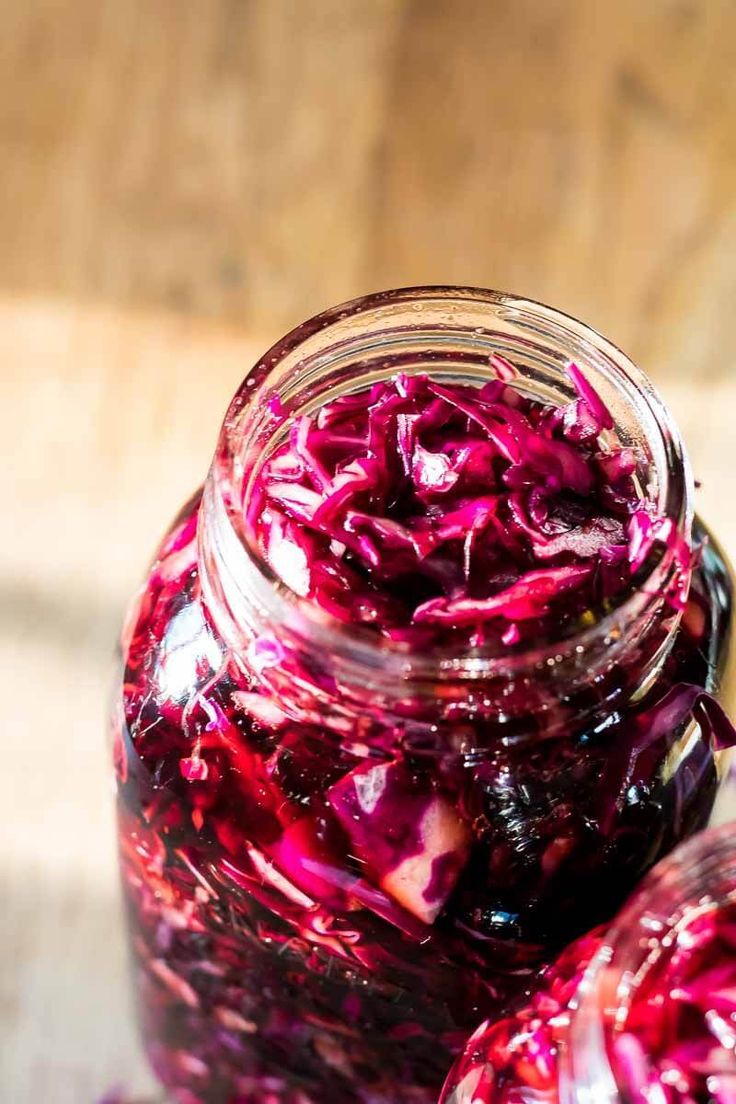 two jars filled with red cabbage sitting on top of a table