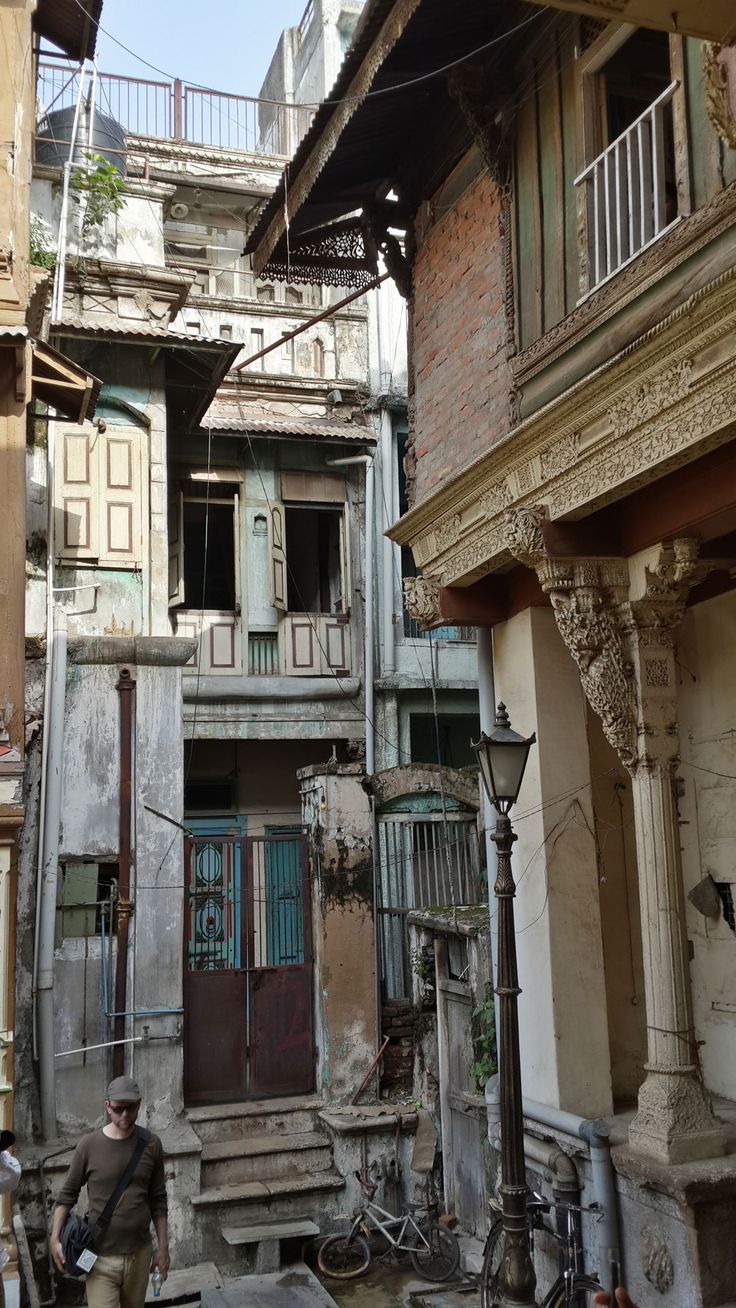 two people are walking through an alleyway with old buildings in the backgrouds