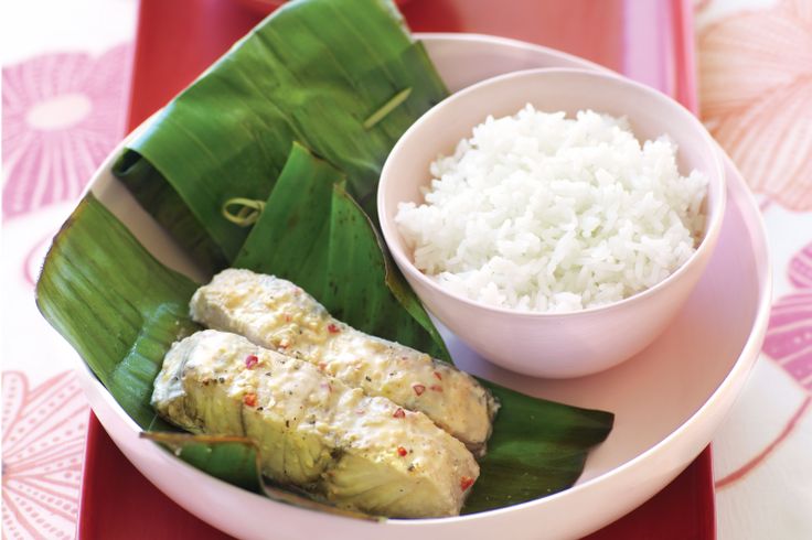 a white plate topped with rice and meat next to green leafy vegetables on a red tray