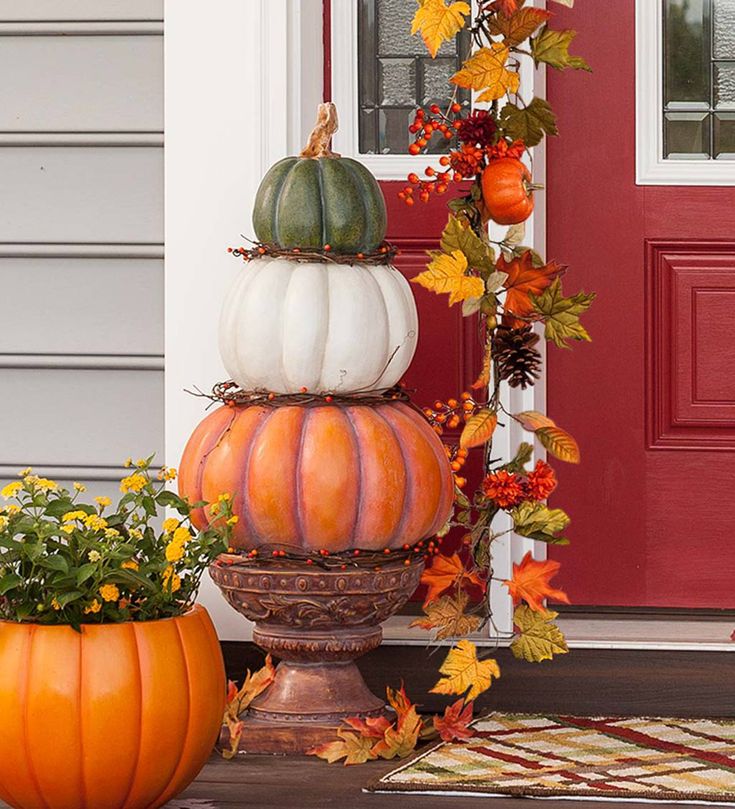 three pumpkins are stacked on top of each other in front of a red door