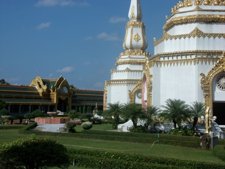 a large white building with gold trim and a clock on it's face in the middle of a park