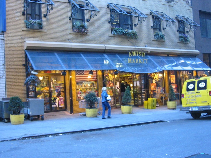 a yellow van parked in front of a store on the side of a street with people walking by