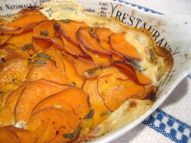 a casserole dish with potatoes and bacon in it on a blue and white checkered tablecloth