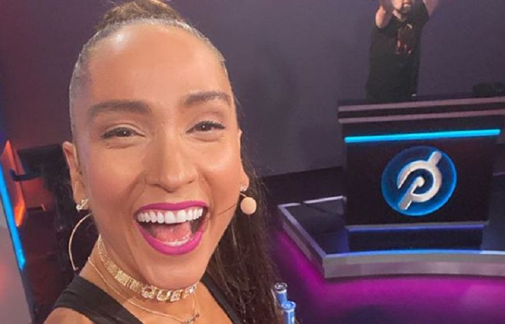 a smiling woman in front of a microphone on the set of an american idol show