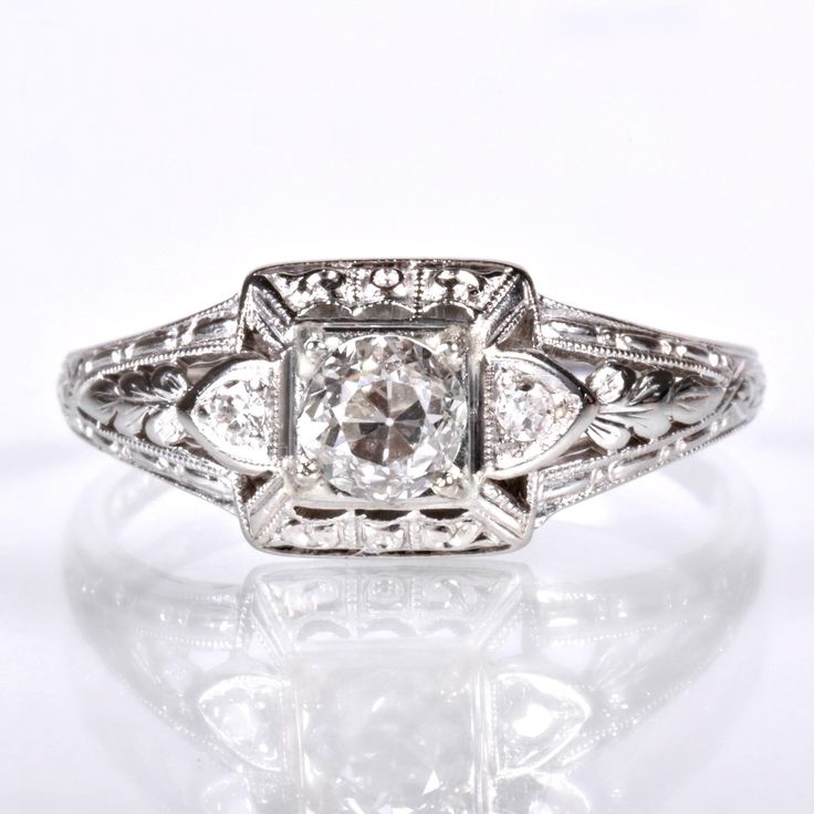 an antique style diamond ring with filigrees on the sides and center stone