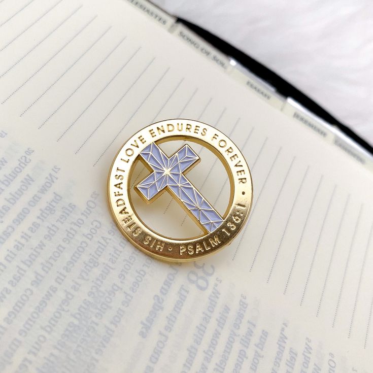 a pin with a cross on it sitting on top of an open book