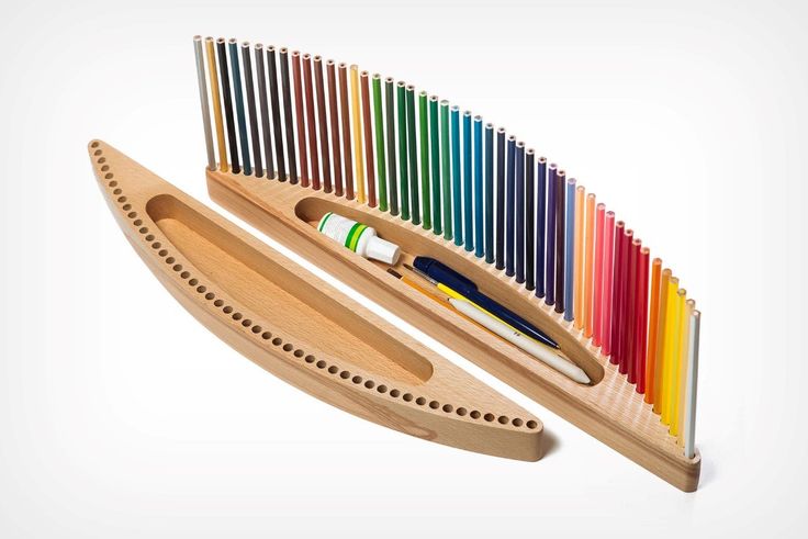 a wooden pen holder with colored pencils in it and a ruler next to it