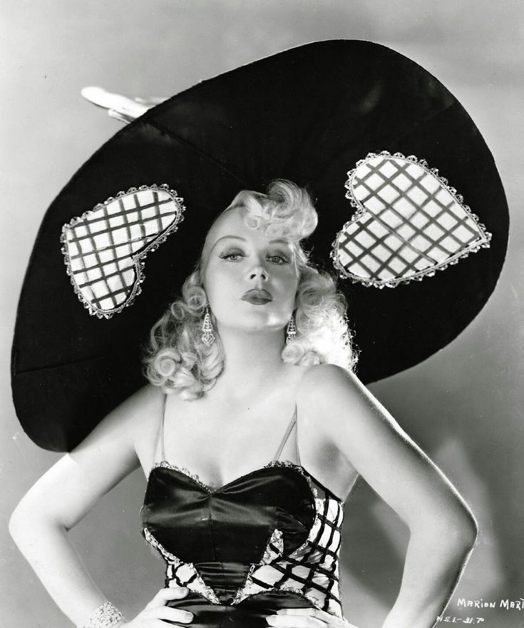 a woman in a dress and hat poses for the camera