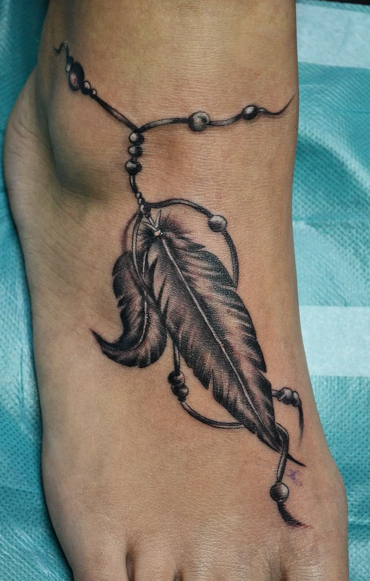 a foot with a feather and beads on it