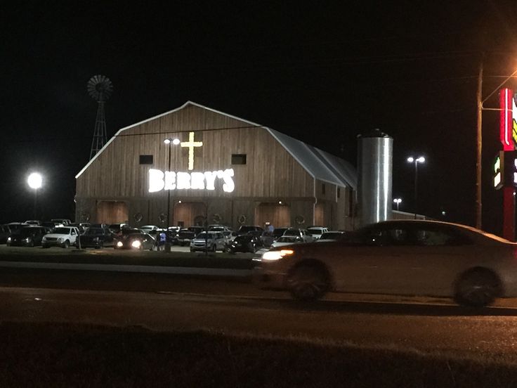 a car driving past a barn at night