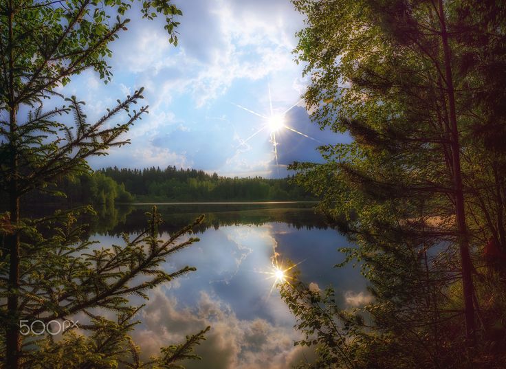 the sun shines brightly through the clouds over a lake surrounded by trees and water