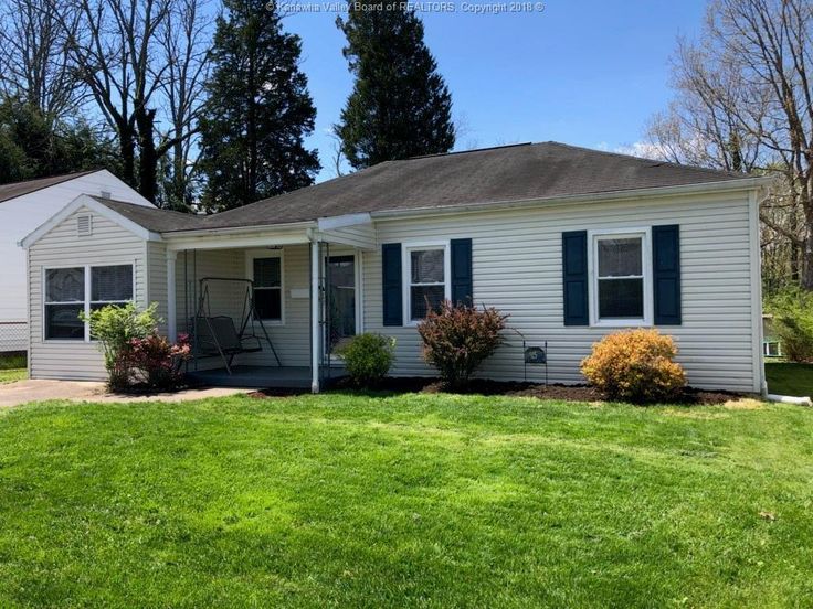 a white house with blue shutters and green grass in the front yard on a sunny day