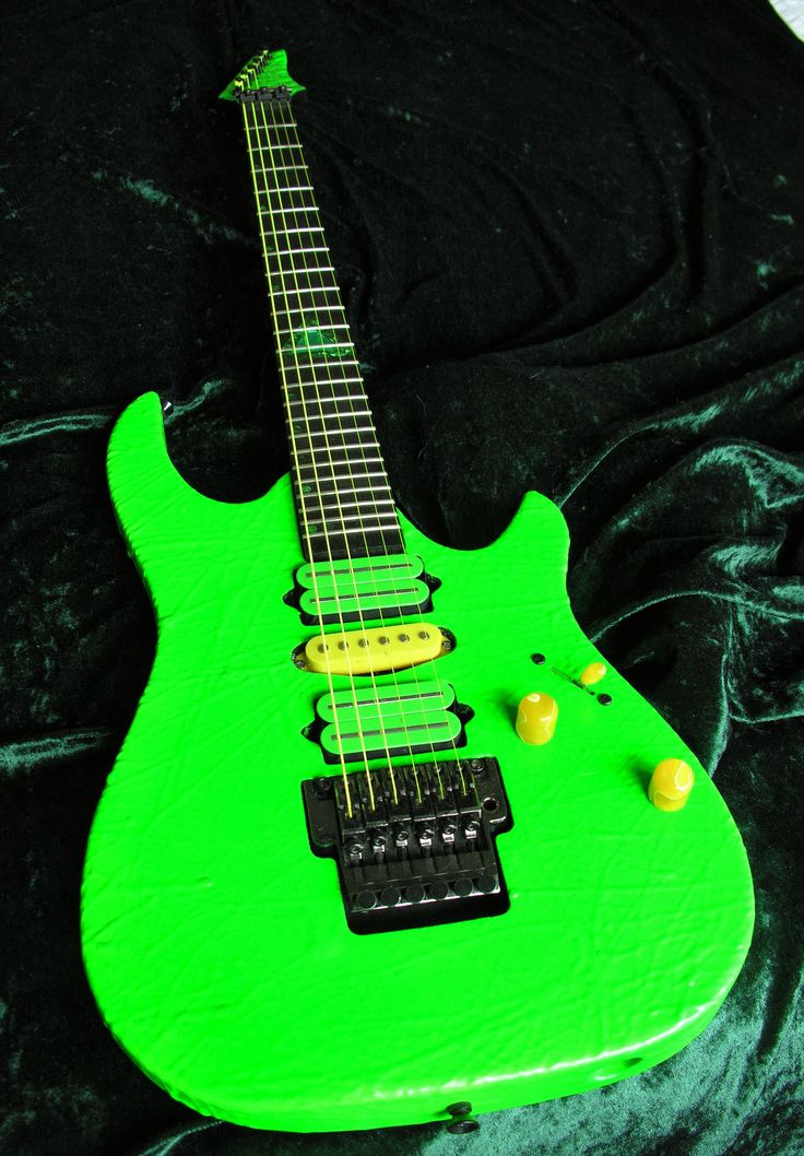 a green electric guitar sitting on top of a black cloth