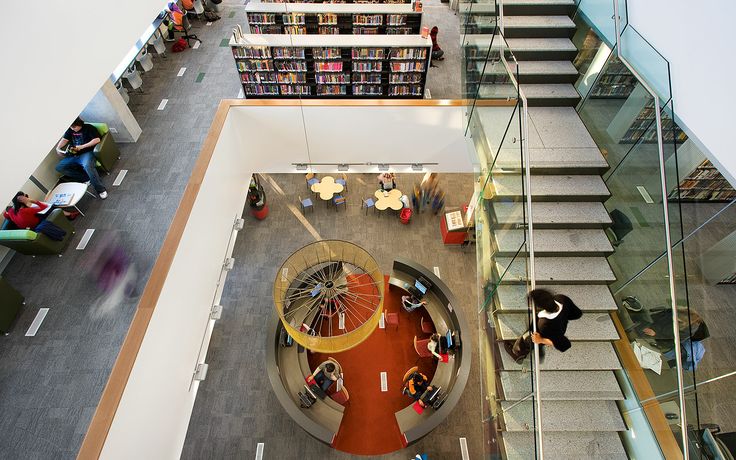 an overhead view of people sitting at tables and standing around in a lobby with glass walls