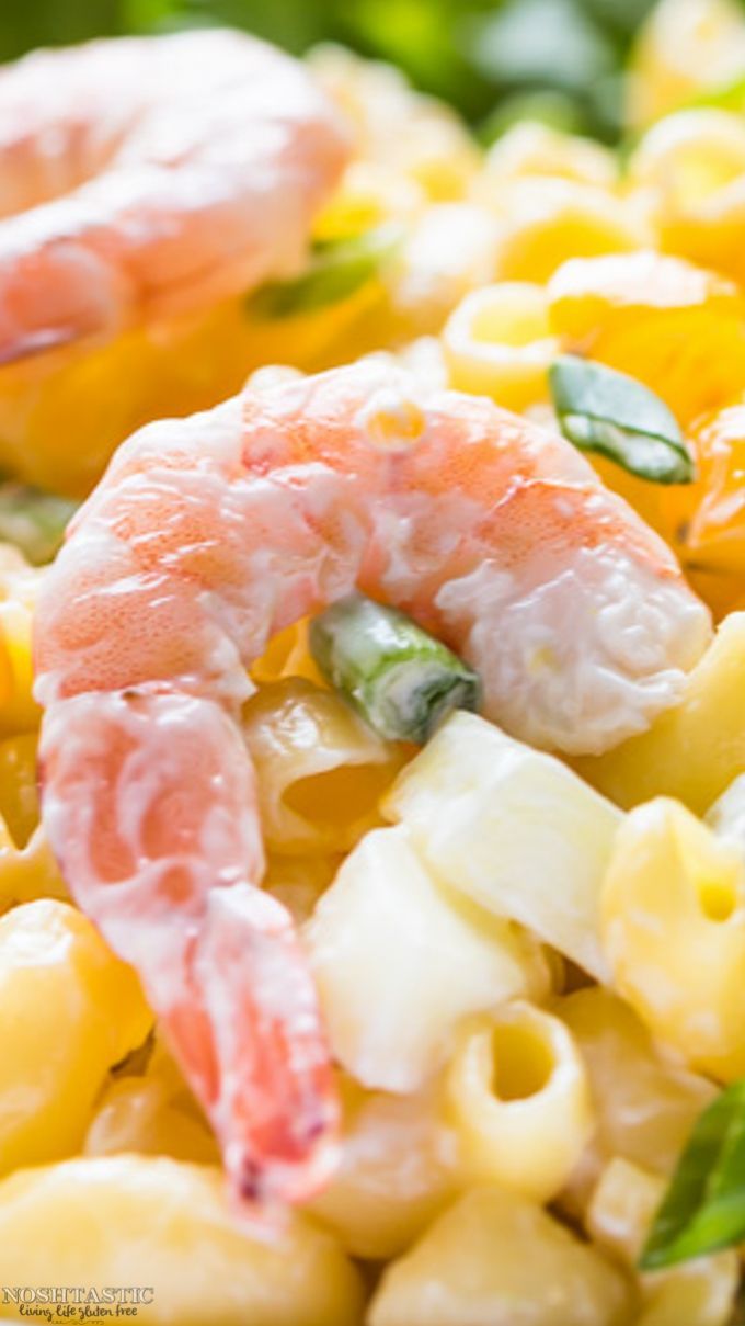 shrimp and macaroni salad on a white plate with green garnishes