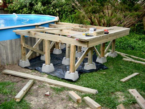 a wooden table sitting in the middle of a yard next to an above ground pool