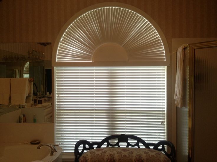 a bath room with a tub and a window covered in blinds next to a sink