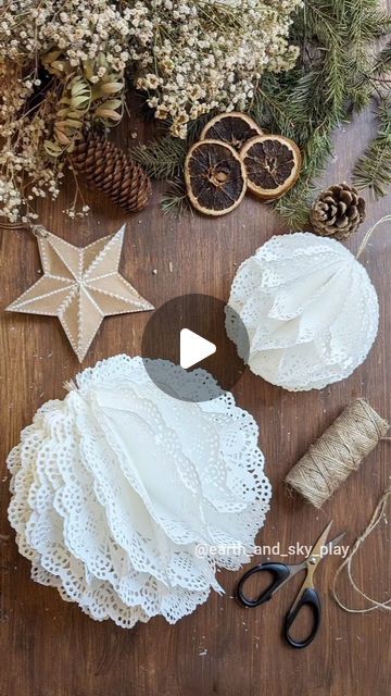 lace and twine are laid out on a wooden table with pine cones, scissors, string, and other items