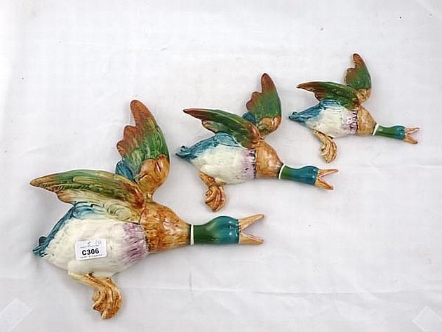 three small ceramic birds sitting on top of each other in the shape of two ducks