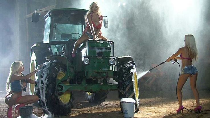 two women in bathing suits spray water on a tractor