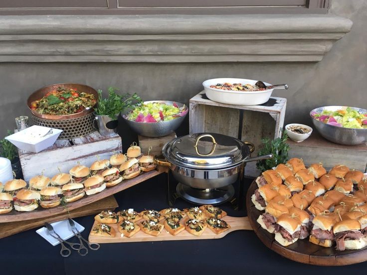 an assortment of food is displayed on wooden platters, including sandwiches and salads