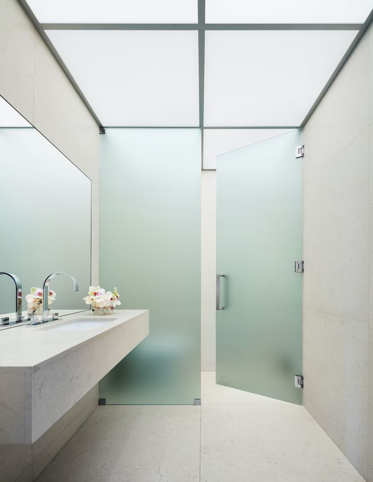 a bathroom with two sinks and a large glass shower door in the middle of it