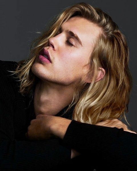 a man with long blonde hair is posing for the camera and has his eyes closed