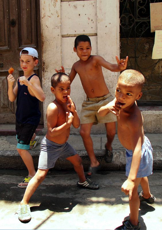 four young boys are playing outside on the street and one boy is holding something in his hand