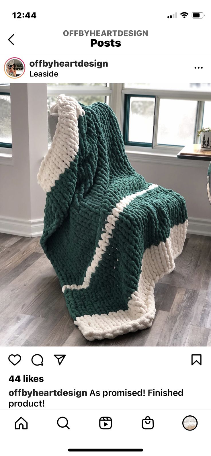 a green and white blanket sitting on top of a wooden floor next to a window