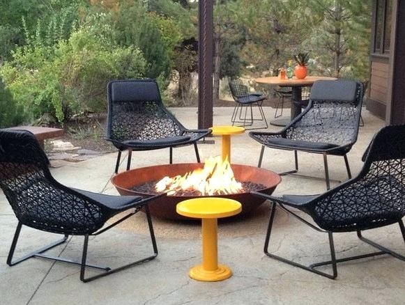 an outdoor fire pit with four chairs around it and a table on the other side