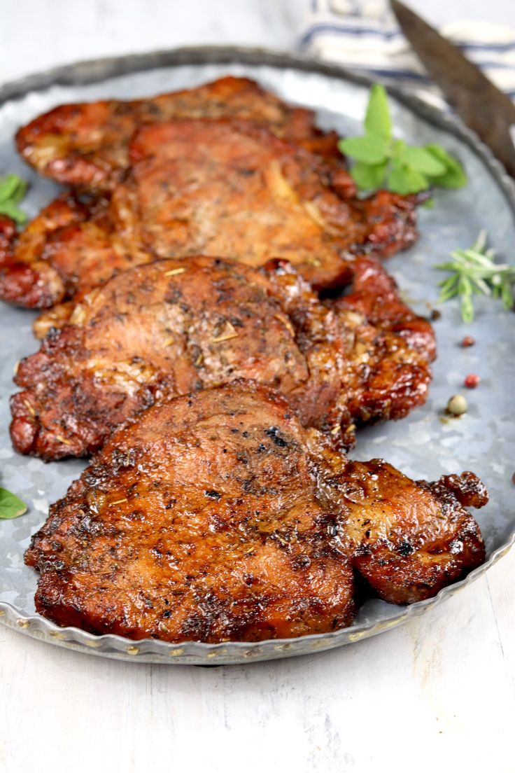 three pieces of meat sitting on top of a metal plate next to a knife and fork