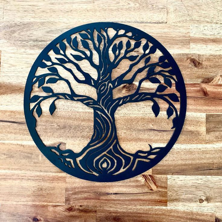 the tree of life has been cut out from wood and is hanging on a wall