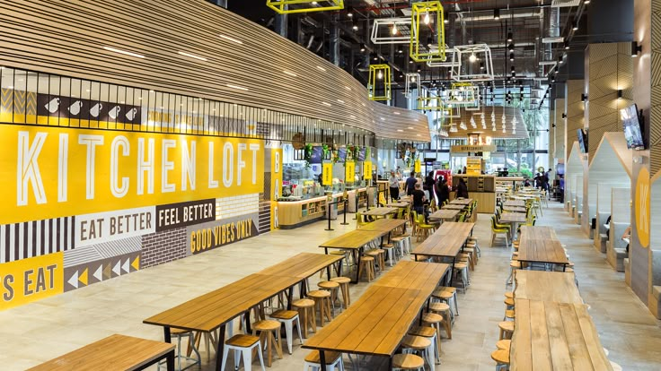 the interior of a restaurant with wooden benches and yellow signs hanging from the ceiling above