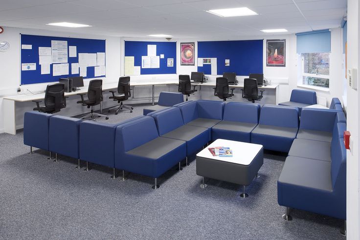 an office with blue couches and white tables