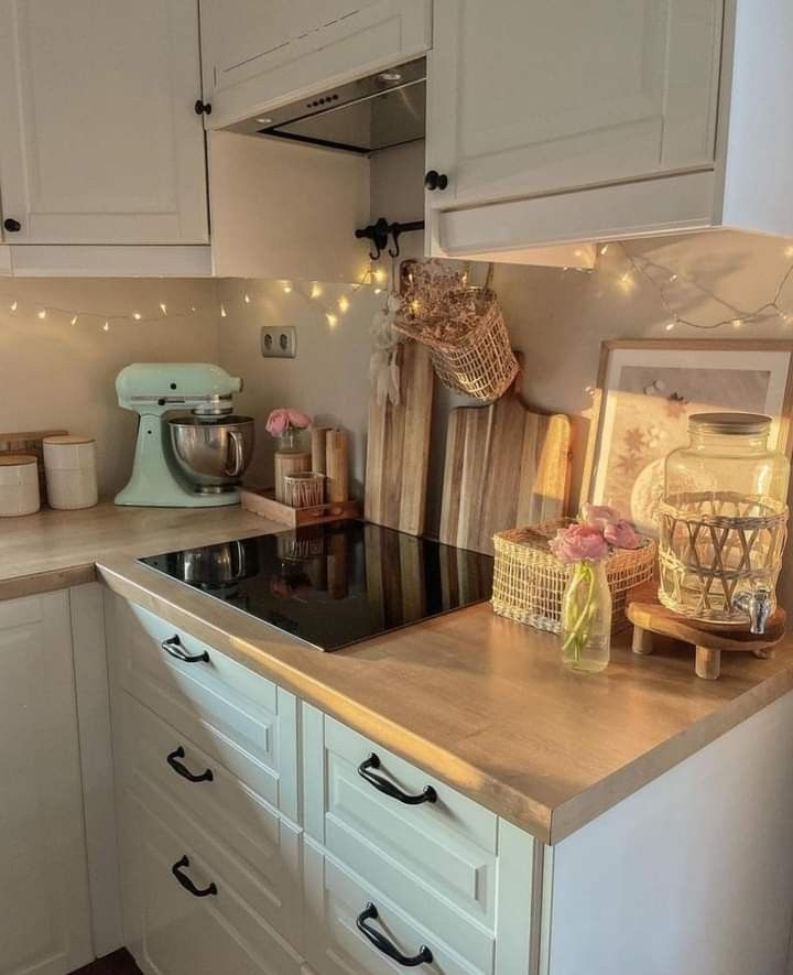 a kitchen with white cabinets and lights on the counter top, along with other appliances