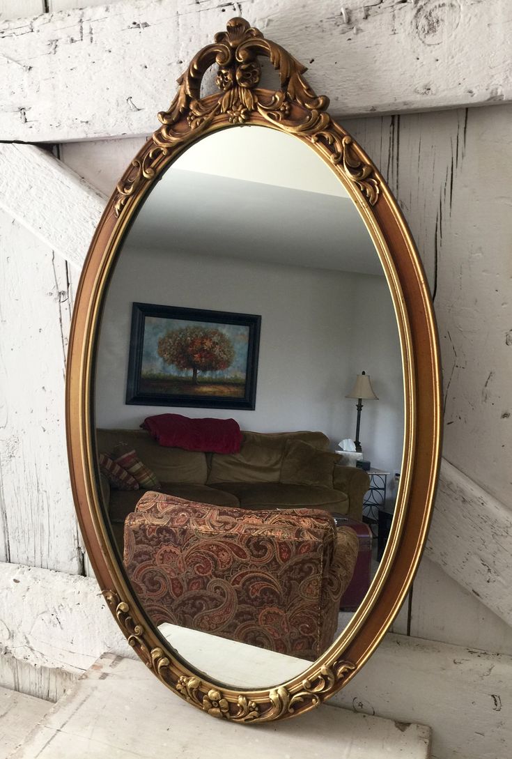 an ornate gold framed mirror hanging on the side of a white painted wall in a living room