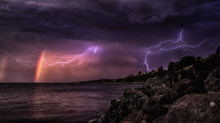 a rainbow is seen in the distance as it appears to be overcast with lightning