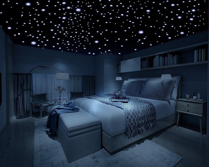 a bed room with a large bed under a sky filled with star shaped lights on the ceiling