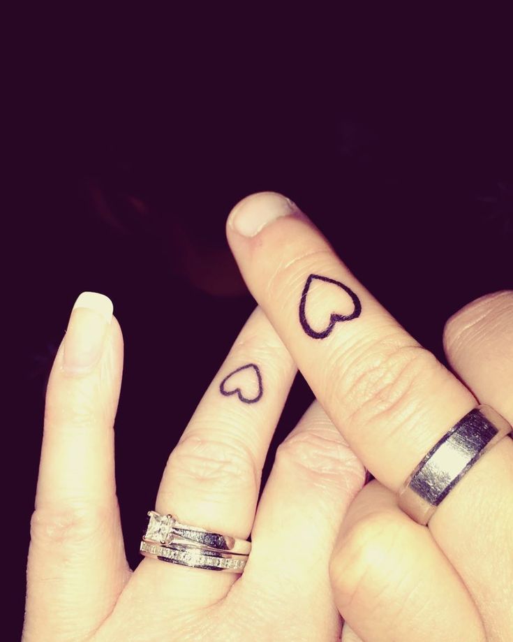 two people with wedding rings on their fingers holding each other's fingers and hearts