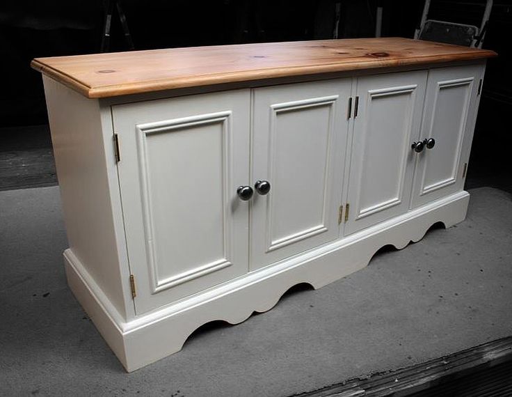 a white cabinet with wooden top sitting on the ground