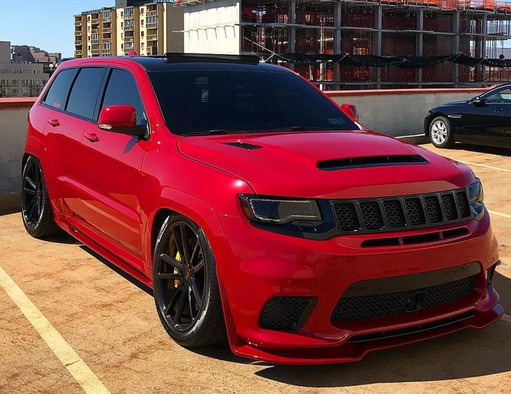 a red jeep is parked in a parking lot