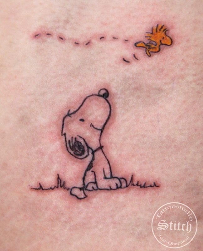 a small tattoo of a dog and a fish on the back of a woman's stomach