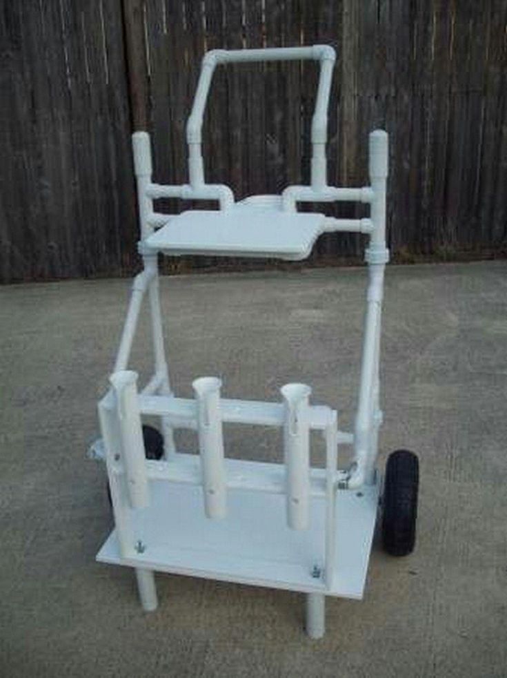 a white cart sitting on top of a cement ground next to a wooden fence with black wheels