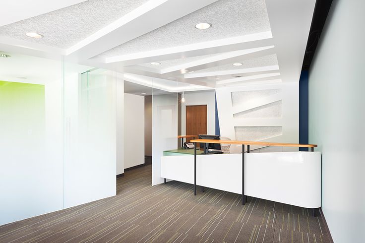 an empty office with white walls and wood flooring on the side, along with glass partitions